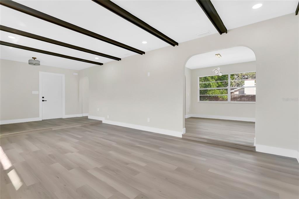 A living area with light wood flooring, dark ceiling beams, and an arched entryway — 330 ELKHORN COURT, WINTER PARK, FL
