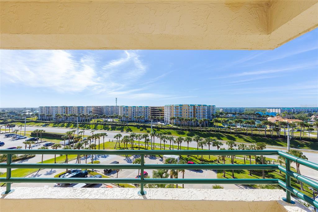 A view from a balcony overlooking a parking lot, palm trees, and large apartment buildings — 4631 S ATLANTIC AVENUE UNIT 8601, PONCE INLET, FL