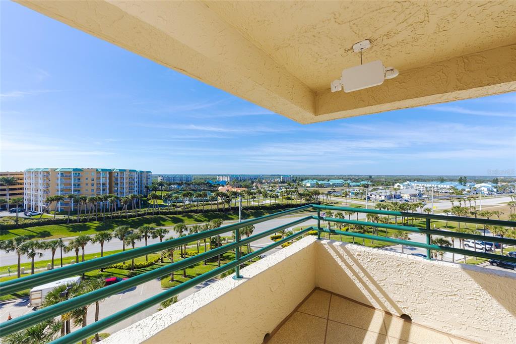 A balcony with a green metal railing overlooks a parking lot, palm trees, and buildings — 4631 S ATLANTIC AVENUE UNIT 8601, PONCE INLET, FL