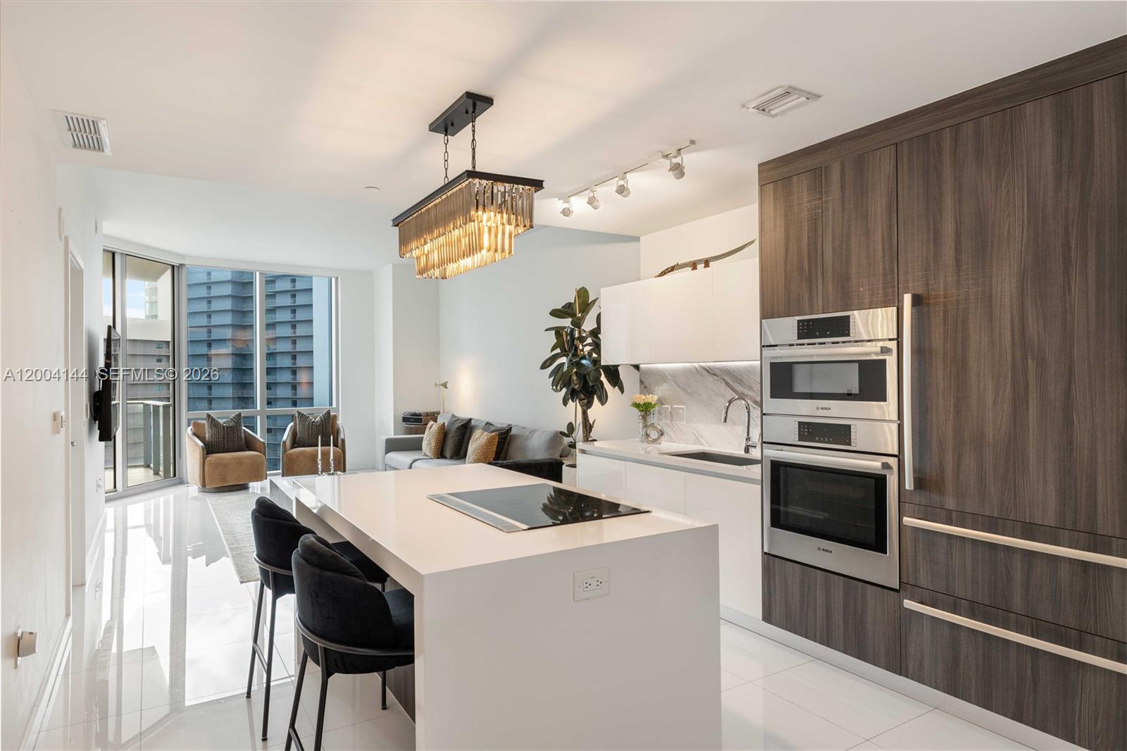 A modern kitchen with a white island and dark wood cabinetry opens to a living area — 851 NE 1st Ave # 4405, Miami FL 33132, MIAMI, FL