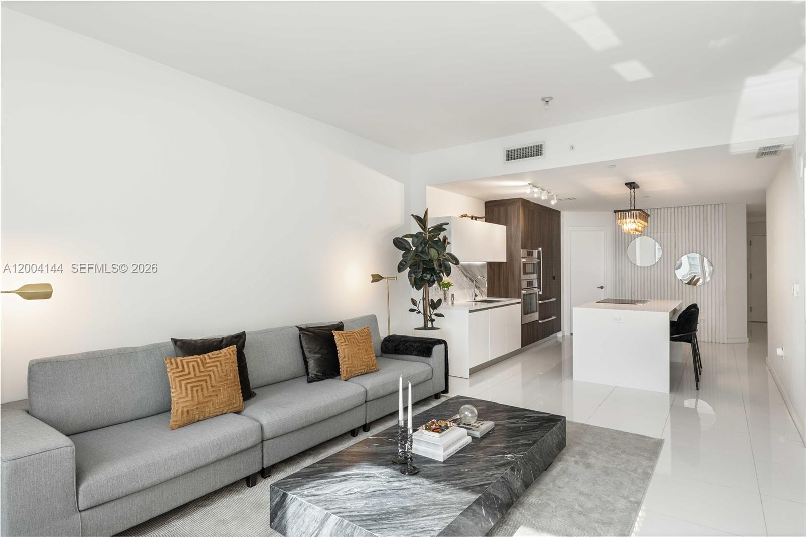 A modern living room features a grey sofa, marble coffee table, and an open kitchen — 851 NE 1st Ave # 4405, Miami FL 33132, MIAMI, FL