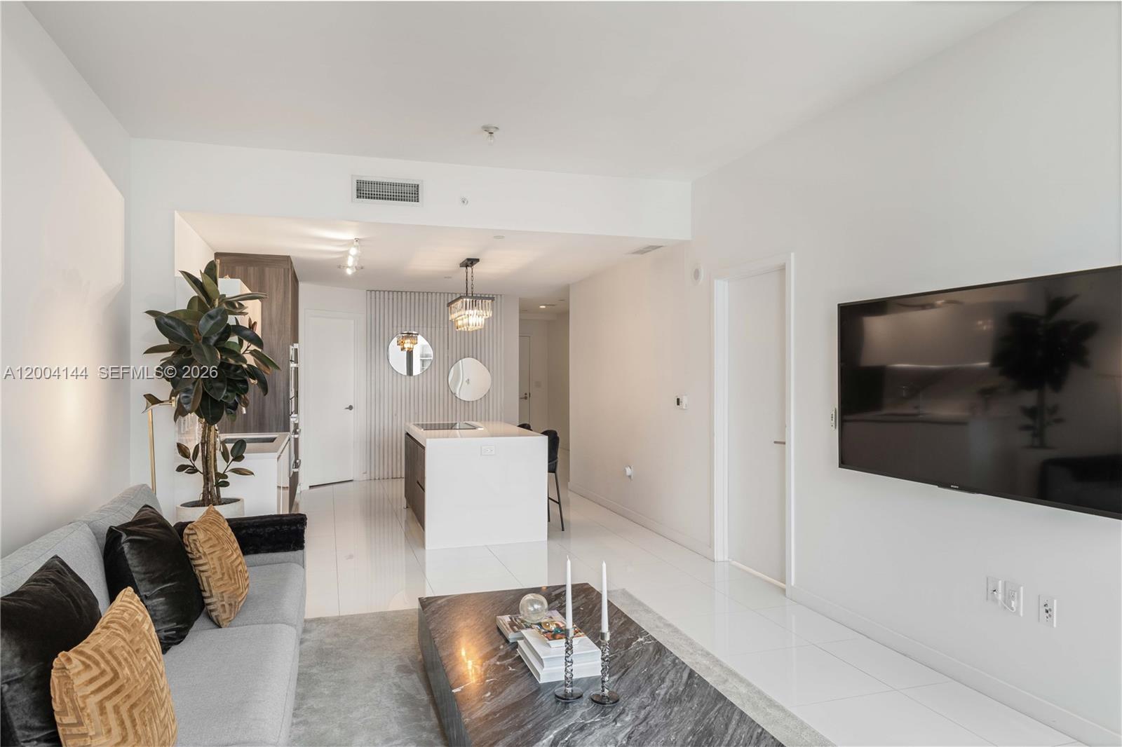 A modern living room features a grey sofa, marble coffee table, and an open kitchen — 851 NE 1st Ave # 4405, Miami FL 33132, MIAMI, FL