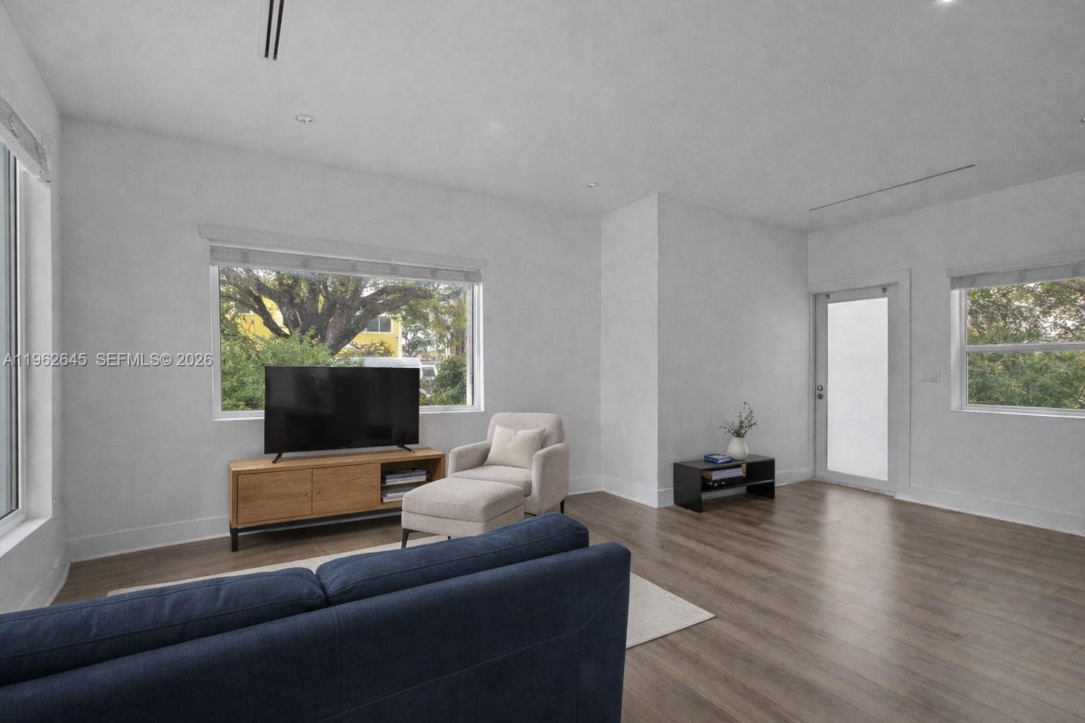 A living room features light wood flooring, white walls, a blue sofa, and large windows — 2900 SW 4th St, Miami FL 33135, MIAMI, FL