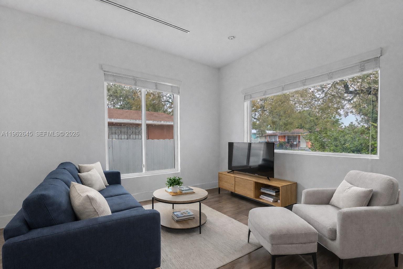 A living room features a blue sofa, light gray armchair with ottoman, and wooden media console — 2900 SW 4th St, Miami FL 33135, MIAMI, FL