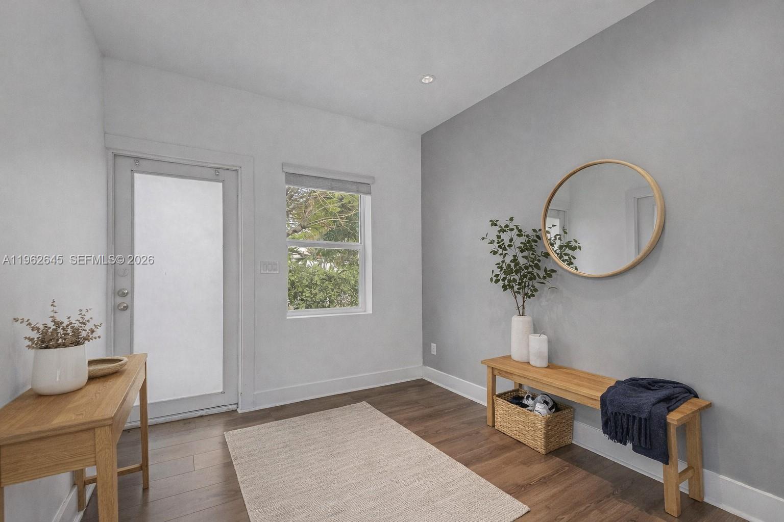 An entryway features a wooden bench, a round mirror, a console table, and wood flooring — 2900 SW 4th St, Miami FL 33135, MIAMI, FL