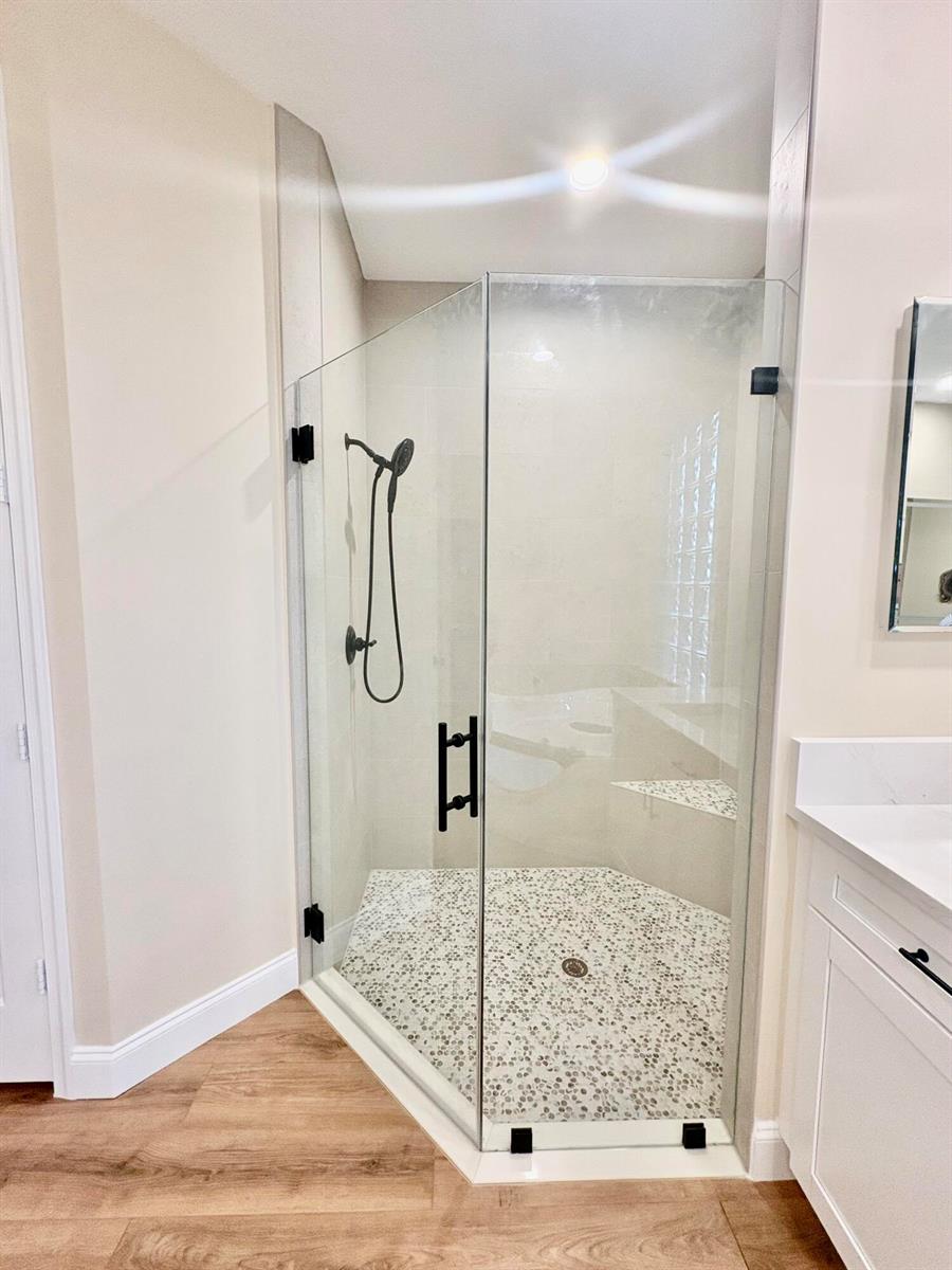 A corner glass shower with black hardware and a pebble tile floor in a bathroom — 8958 Terni Lane, Boynton Beach FL 33472, BOYNTON BEACH, FL