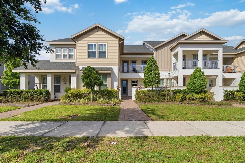 A two-story residential building with tan siding, a brick walkway, and a covered front porch — 13444 STODDART AVENUE, ORLANDO, FL