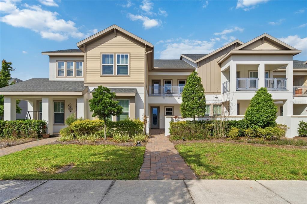 The exterior of a two-story residential building features tan siding, white stucco, and a walkway — 13444 STODDART AVENUE, ORLANDO, FL