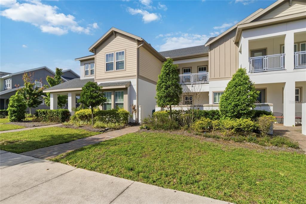 A two-story residential building with beige siding, white stucco, and a paved walkway — 13444 STODDART AVENUE, ORLANDO, FL