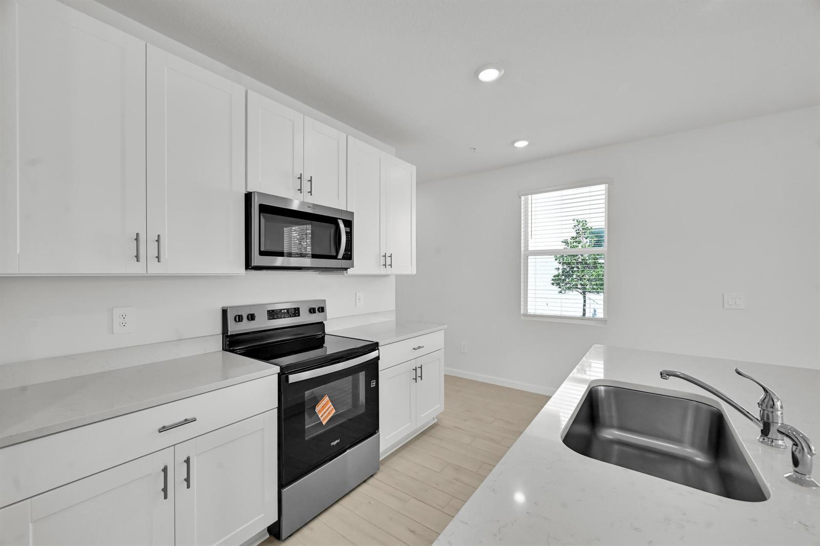 A modern kitchen features white cabinets, stainless steel appliances, quartz countertops, and a kitchen island — 636 Salisbury Circle, Fort Pierce FL 34982, FORT PIERCE, FL