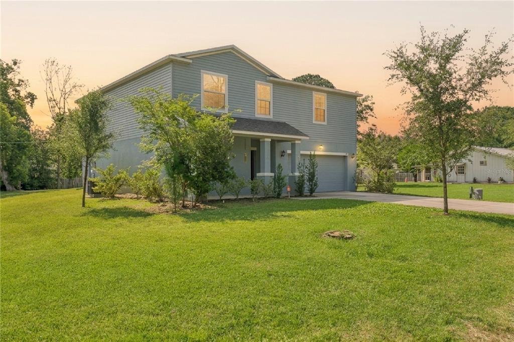 A two-story blue house with a front porch and an attached garage on a lawn — 1995 5TH AVENUE, DELAND, FL