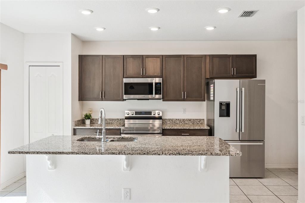 A kitchen with dark wood cabinets, granite countertops, stainless steel appliances, and a central island — 1995 5TH AVENUE, DELAND, FL
