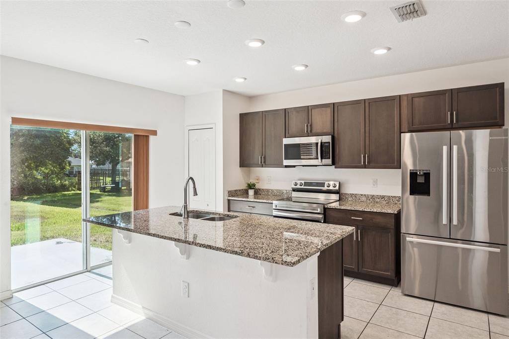 A kitchen with dark wood cabinets, granite countertops, stainless steel appliances, and a center island — 1995 5TH AVENUE, DELAND, FL