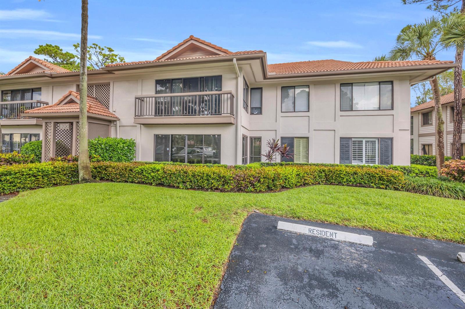 A two-story residential building with a tile roof, balconies, and a landscaped front lawn — 1105 Duncan Circle # 104, Palm Beach Gardens FL 33418, PALM BEACH GARDENS, FL