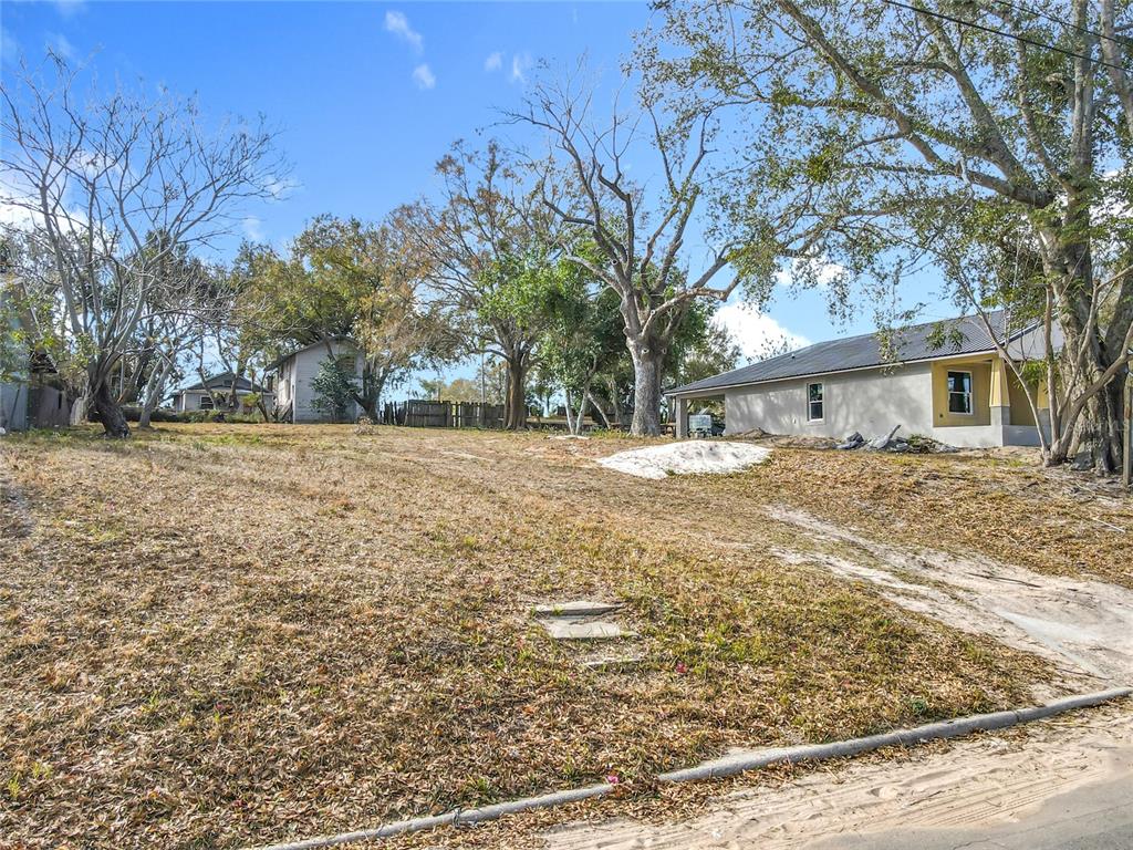 A grassy, sloped lot features a house under construction and several large trees — 309 WEAVER AVENUE, LAKE WALES, FL