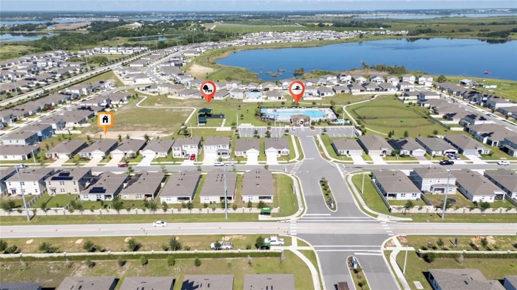 An aerial view shows a suburban neighborhood with houses, a community pool, and a lake — 687 GRIFFON AVENUE, LAKE ALFRED, FL