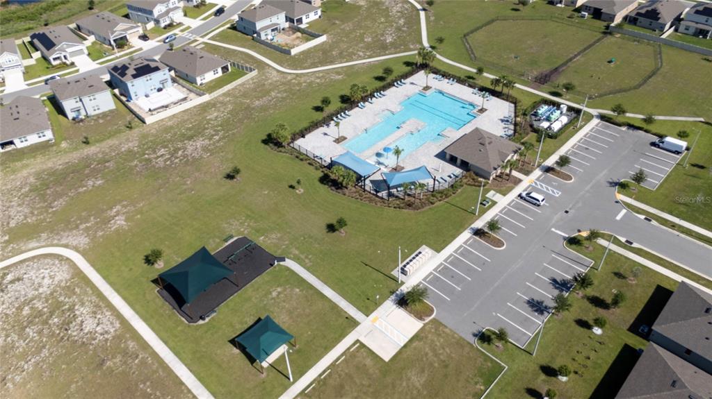 An aerial view shows a community pool, playground, and parking lot surrounded by residential homes — 687 GRIFFON AVENUE, LAKE ALFRED, FL