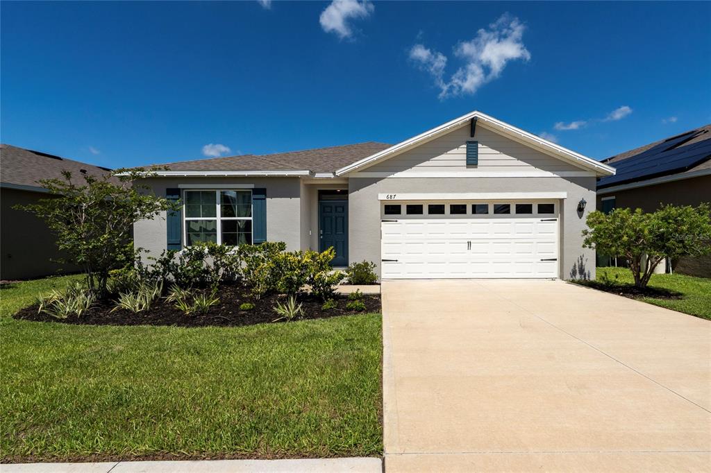A single-story house with a white garage door, gray siding, and a landscaped front yard — 687 GRIFFON AVENUE, LAKE ALFRED, FL