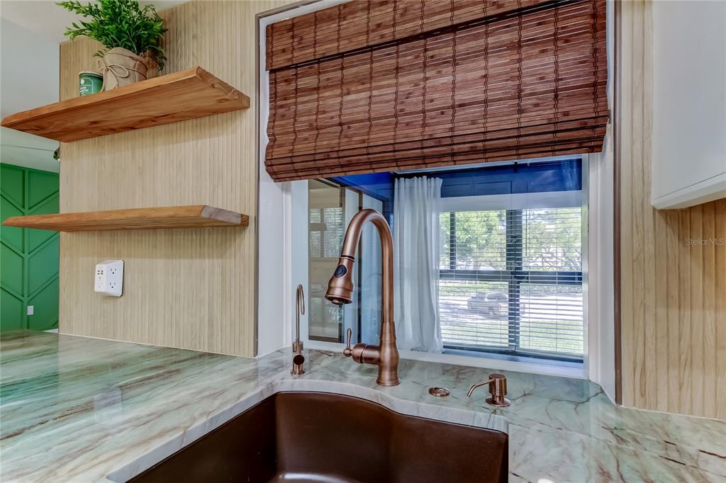 A kitchen with wood-paneled walls, white cabinets, stainless steel appliances, and a stone-topped island — 2673 SABAL SPRINGS CIRCLE UNIT 201, CLEARWATER, FL