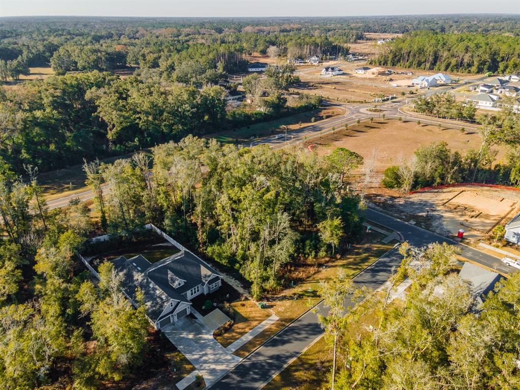 An aerial view shows a suburban house surrounded by trees near a new residential development — Lot 40 SW 7 PLACE, NEWBERRY, FL