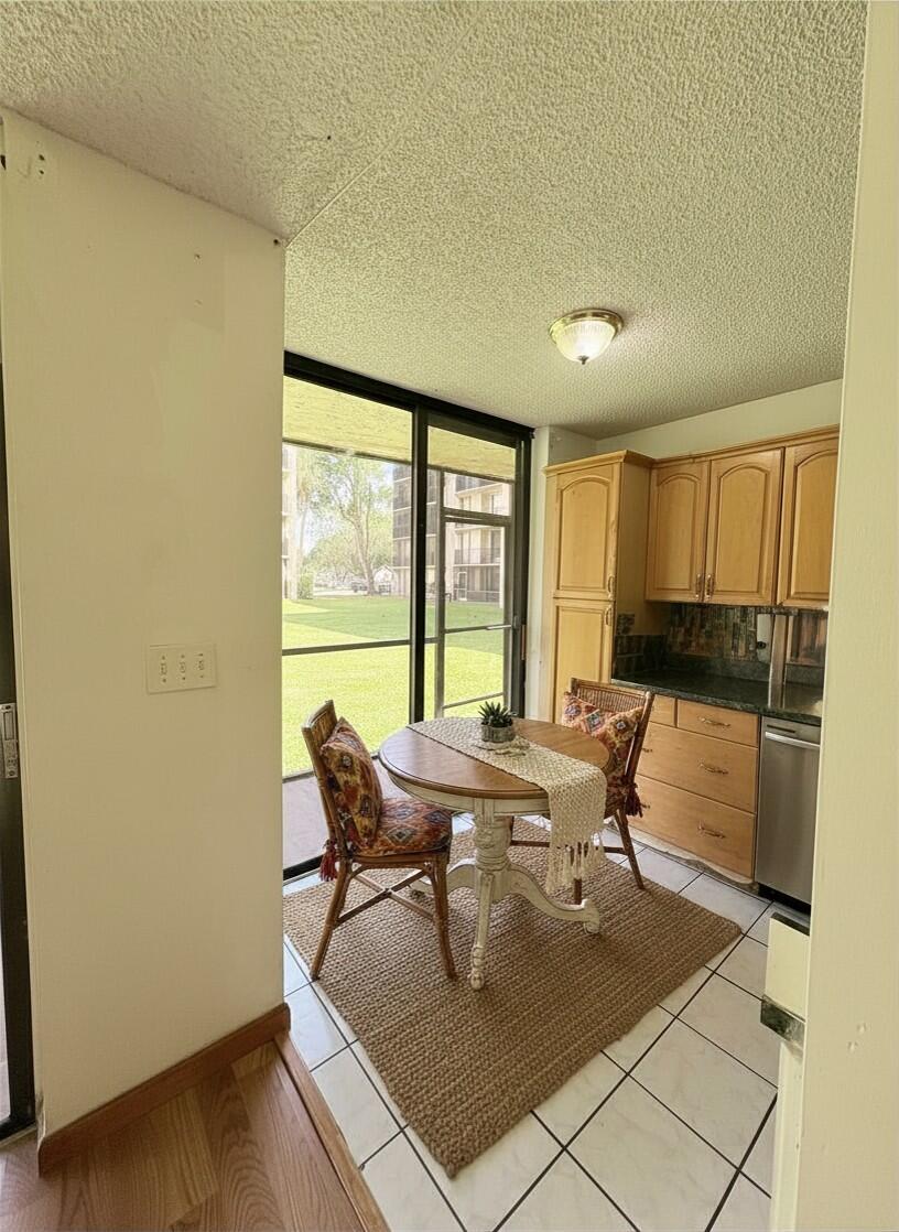 A dining area with a round table, wicker chairs, tile flooring, and a sliding glass door — 3590 Blue Lake Drive # 104, Pompano Beach FL 33064, POMPANO BEACH, FL