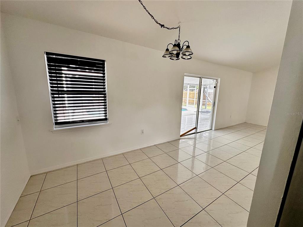 A dining area with white walls, light tile flooring, a chandelier, and sliding glass doors — 1757 QUAIL RIDGE LOOP, KISSIMMEE, FL