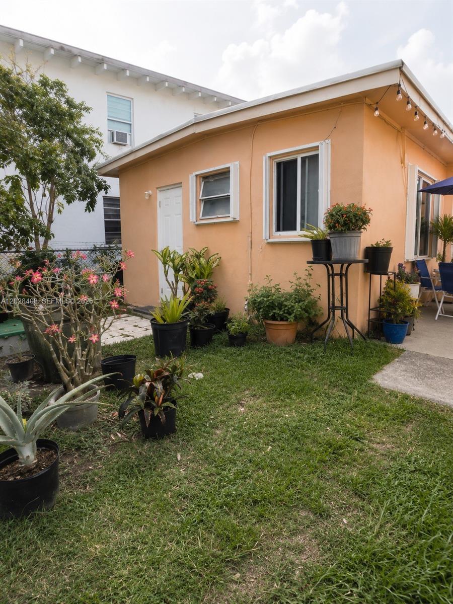 A peach-colored exterior wall of a house features several potted plants on a lawn — 520 SW 6th Ave # 2, Homestead FL 33030, HOMESTEAD, FL