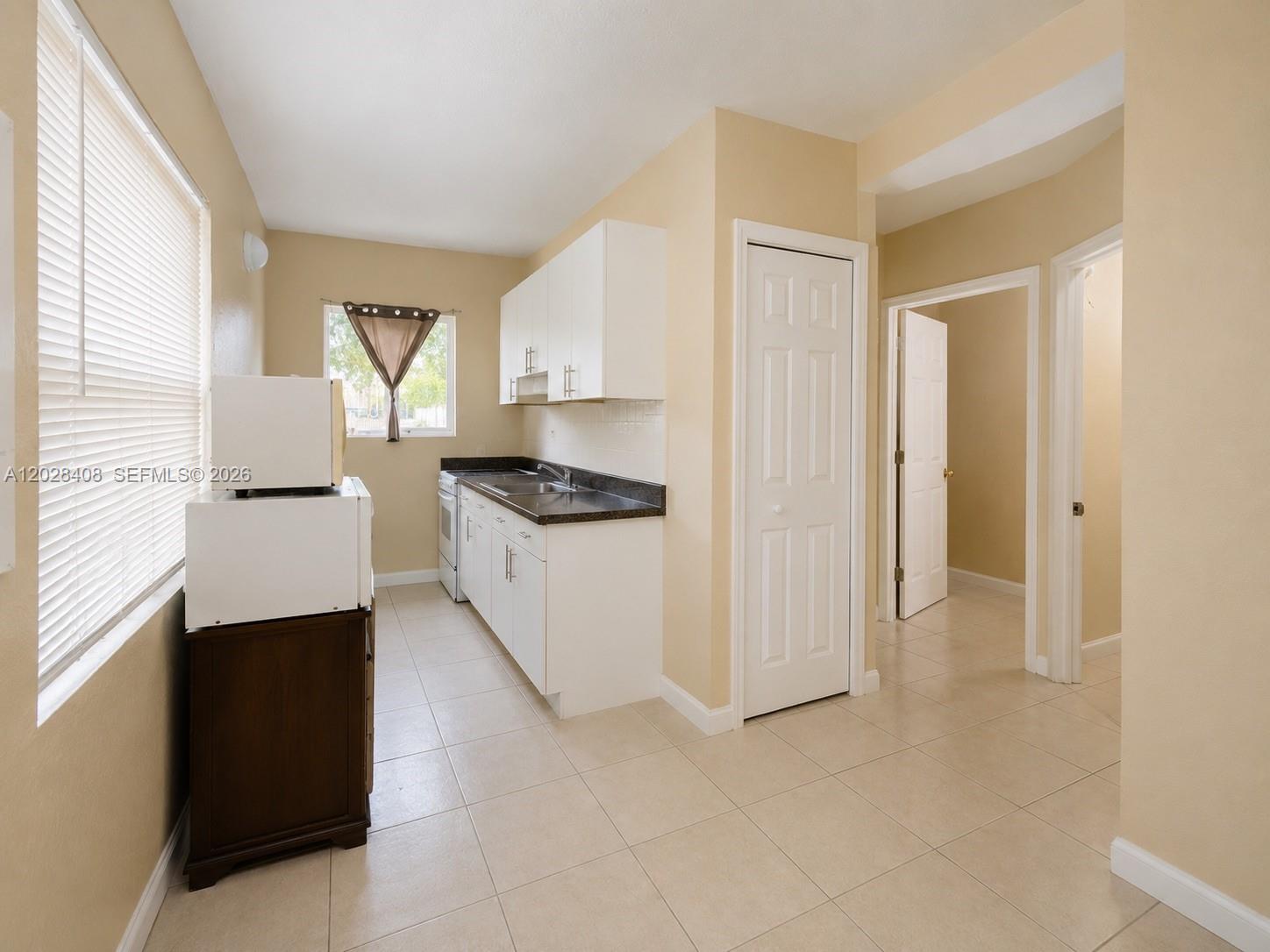 A kitchen features white cabinets, dark countertops, tile flooring, and a window with blinds — 520 SW 6th Ave # 2, Homestead FL 33030, HOMESTEAD, FL