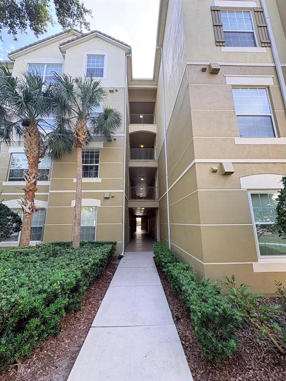 A concrete walkway leads between two tan apartment buildings with palm trees and landscaping — 3344 ROBERT TRENT JONES DRIVE UNIT 10305, ORLANDO, FL