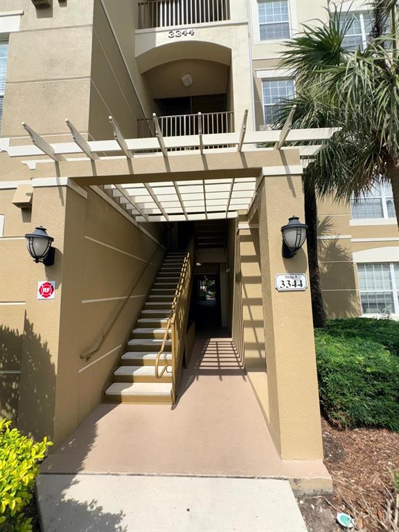 An exterior view of an apartment building entrance featuring a pergola and a staircase — 3344 ROBERT TRENT JONES DRIVE UNIT 10305, ORLANDO, FL