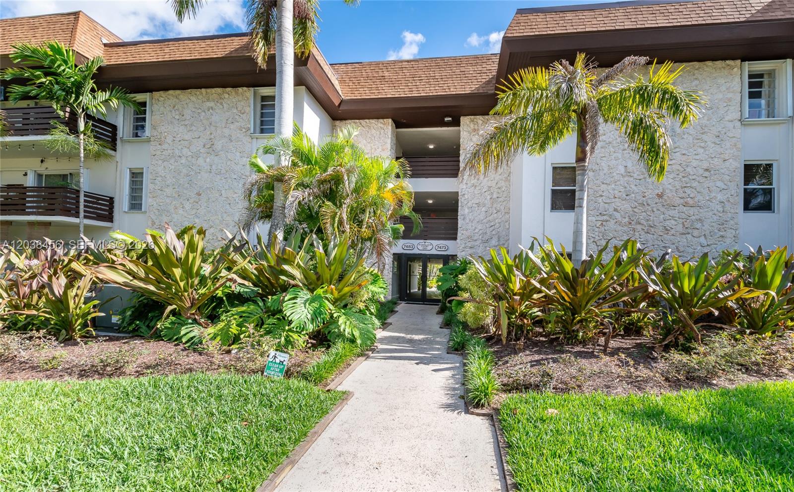 A concrete walkway leads to the entrance of a multi-story building with stone facade walls — 7483 SW 82nd St # A206, Miami FL 33143, MIAMI, FL