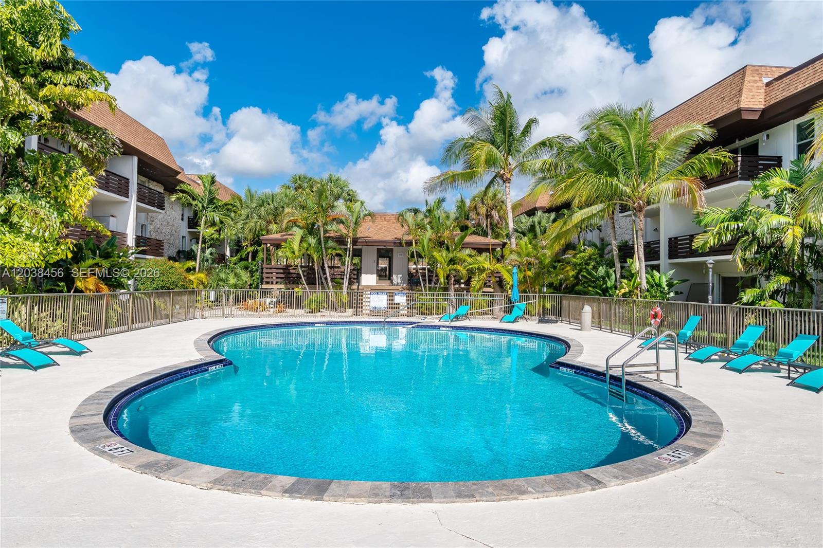 A kidney-shaped swimming pool is surrounded by lounge chairs and palm trees in a courtyard — 7483 SW 82nd St # A206, Miami FL 33143, MIAMI, FL