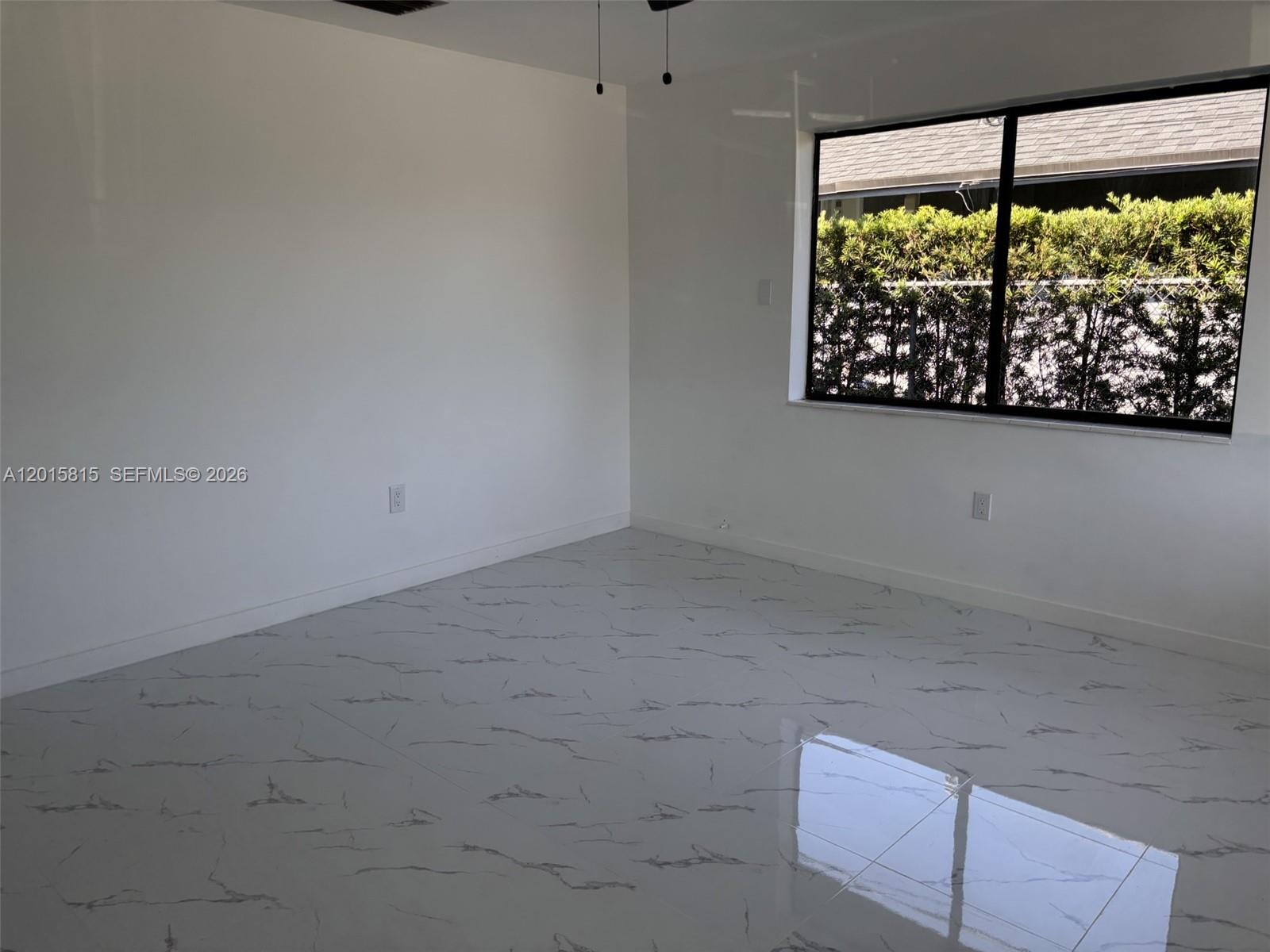 An empty room features white walls, a large window, and glossy marble-patterned tile flooring — 7343 SW 21st St # 0, Miami FL 33155, MIAMI, FL