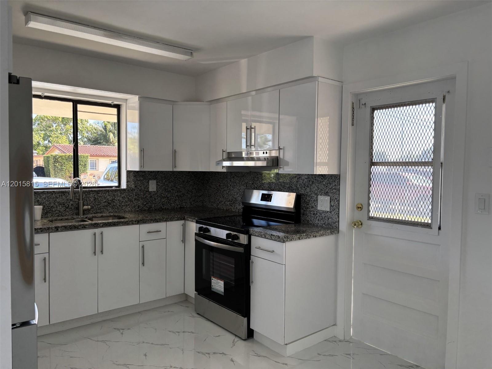 A kitchen with white cabinets, granite countertops, stainless steel appliances, and white marble-patterned tile floors — 7343 SW 21st St # 0, Miami FL 33155, MIAMI, FL