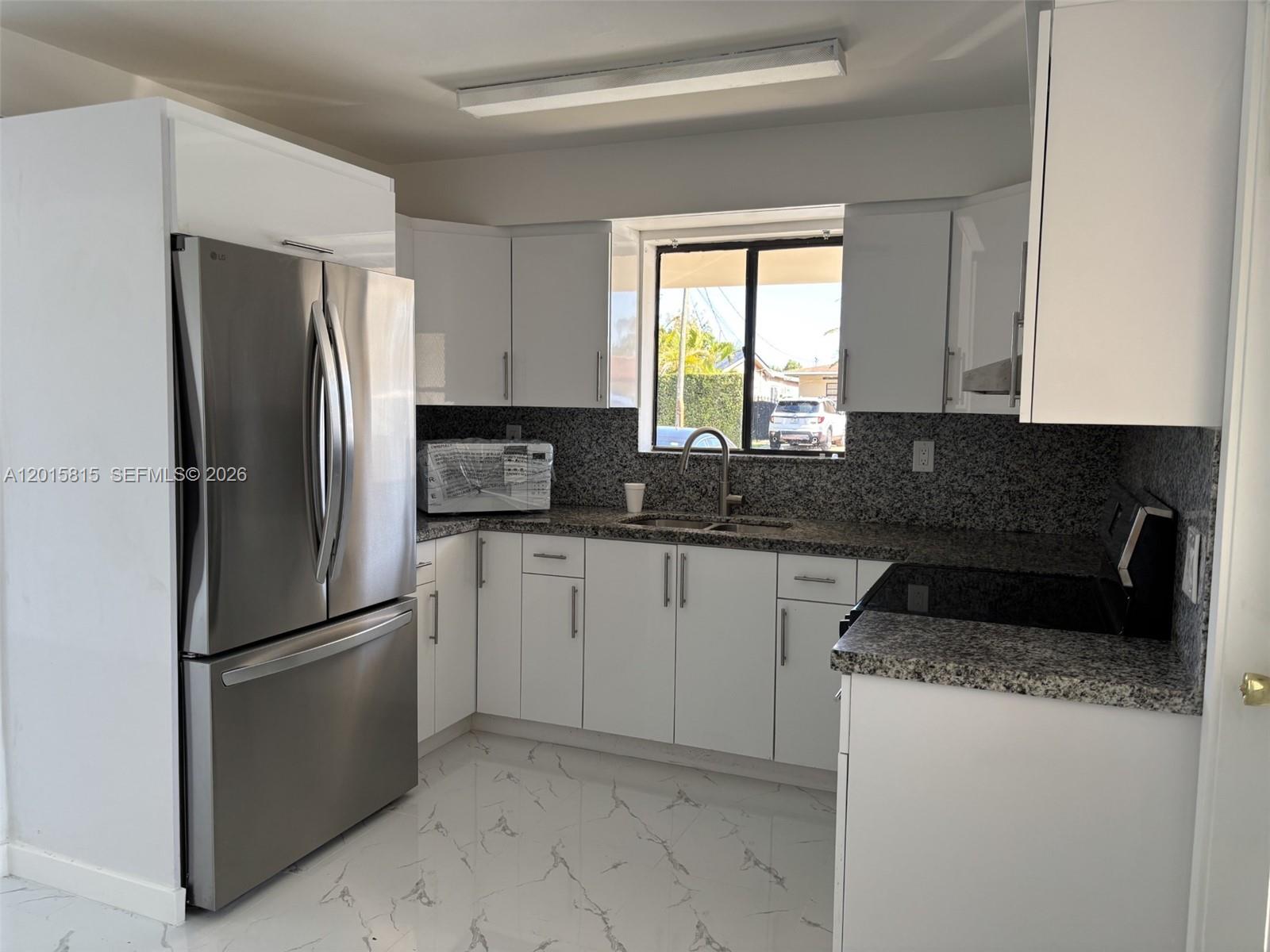 A kitchen features white cabinets, stainless steel appliances, granite countertops, and white marble-patterned tile floors — 7343 SW 21st St # 0, Miami FL 33155, MIAMI, FL