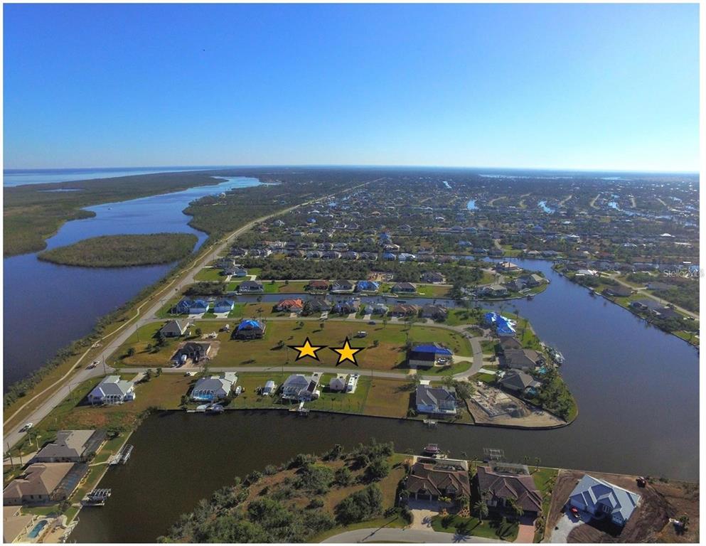 An aerial view shows two vacant residential lots marked with stars in a waterfront community — 15435 ALCOVE CIRCLE, PORT CHARLOTTE, FL