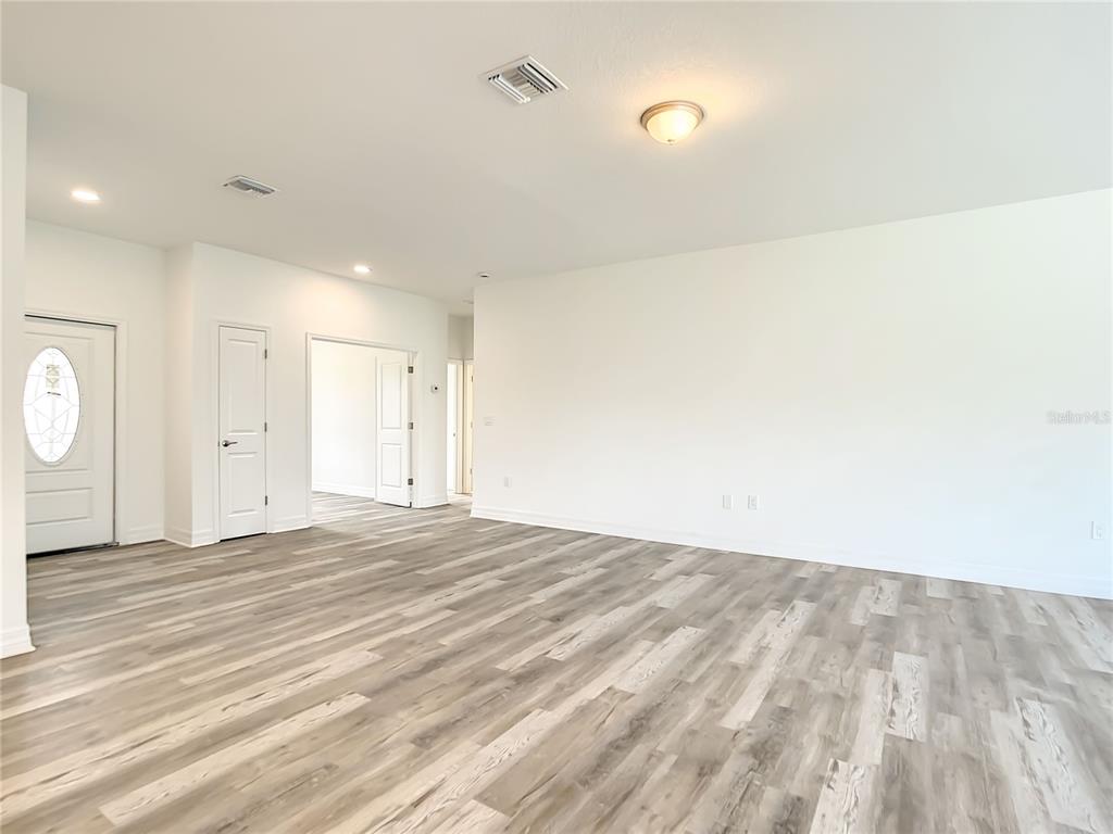 An empty room with white walls, a front door, and light-colored wood-look flooring — 5123 WEATHERTON STREET, NORTH PORT, FL