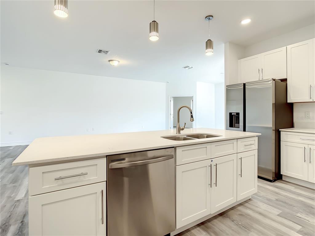 A kitchen island with a stainless steel dishwasher and sink sits before white cabinets — 5123 WEATHERTON STREET, NORTH PORT, FL