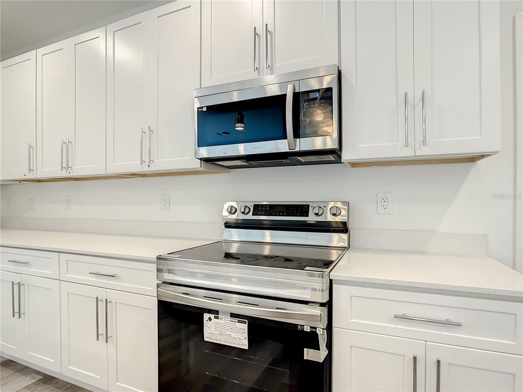 A kitchen features white cabinets, stainless steel appliances, and white countertops — 5123 WEATHERTON STREET, NORTH PORT, FL