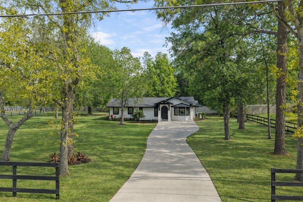 A white single-story house with a dark roof sits at the end of a concrete driveway — 5721 SW 31ST STREET, OCALA, FL