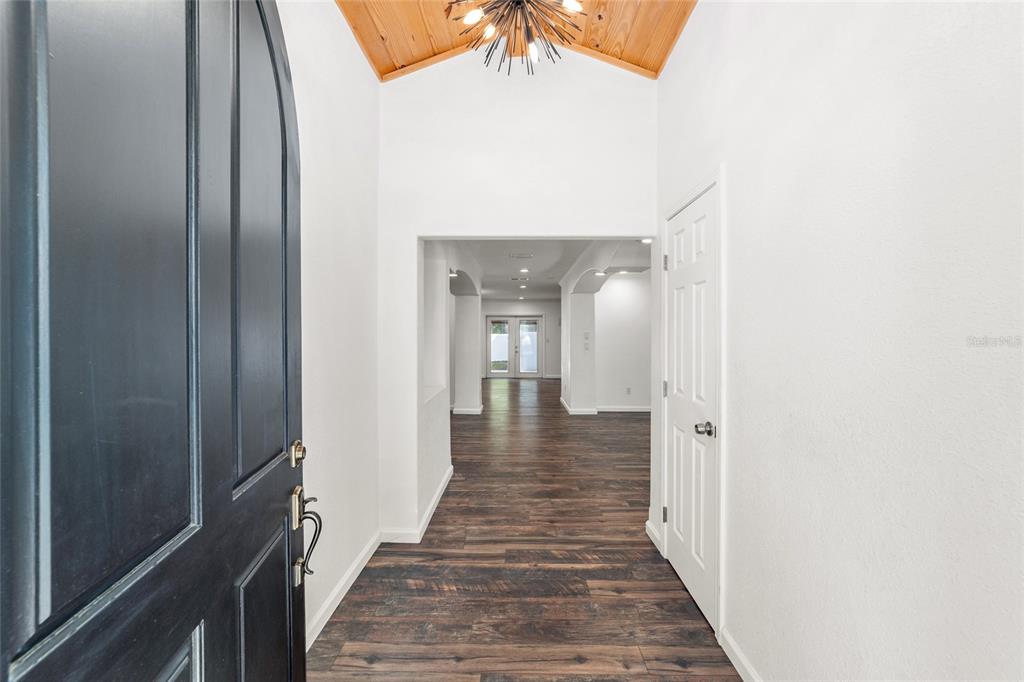 An entryway features dark wood-look flooring, a vaulted wood-paneled ceiling, and a modern light fixture — 5721 SW 31ST STREET, OCALA, FL