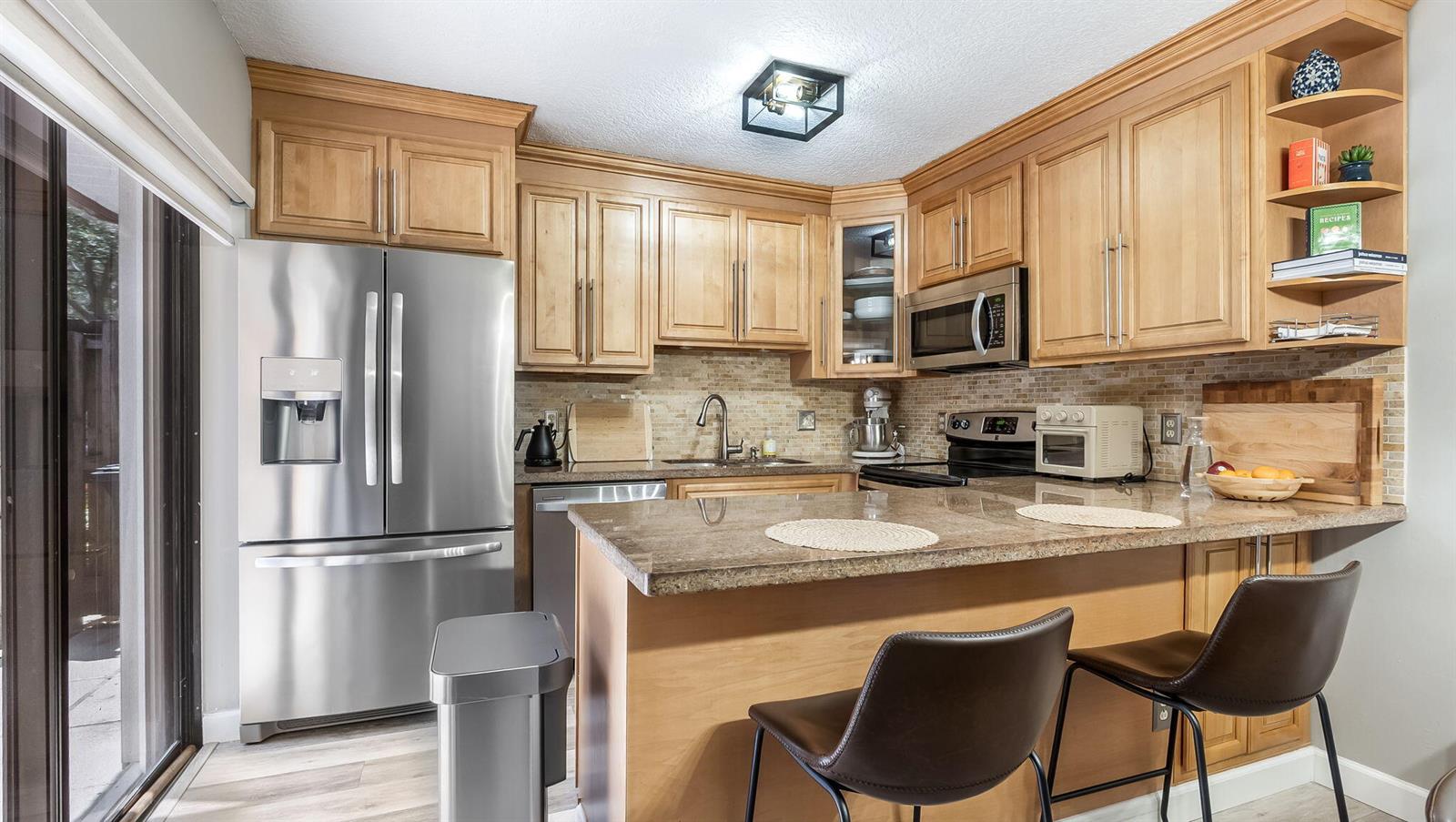 A kitchen with light wood cabinets, stainless steel appliances, and a granite-topped breakfast bar — 725 NW 99th Circle, Plantation FL 33324, PLANTATION, FL