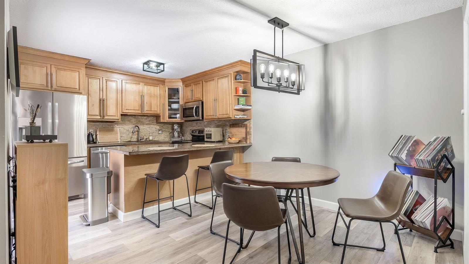 A kitchen with light wood cabinets, granite countertops, and a dining area with a round table — 725 NW 99th Circle, Plantation FL 33324, PLANTATION, FL