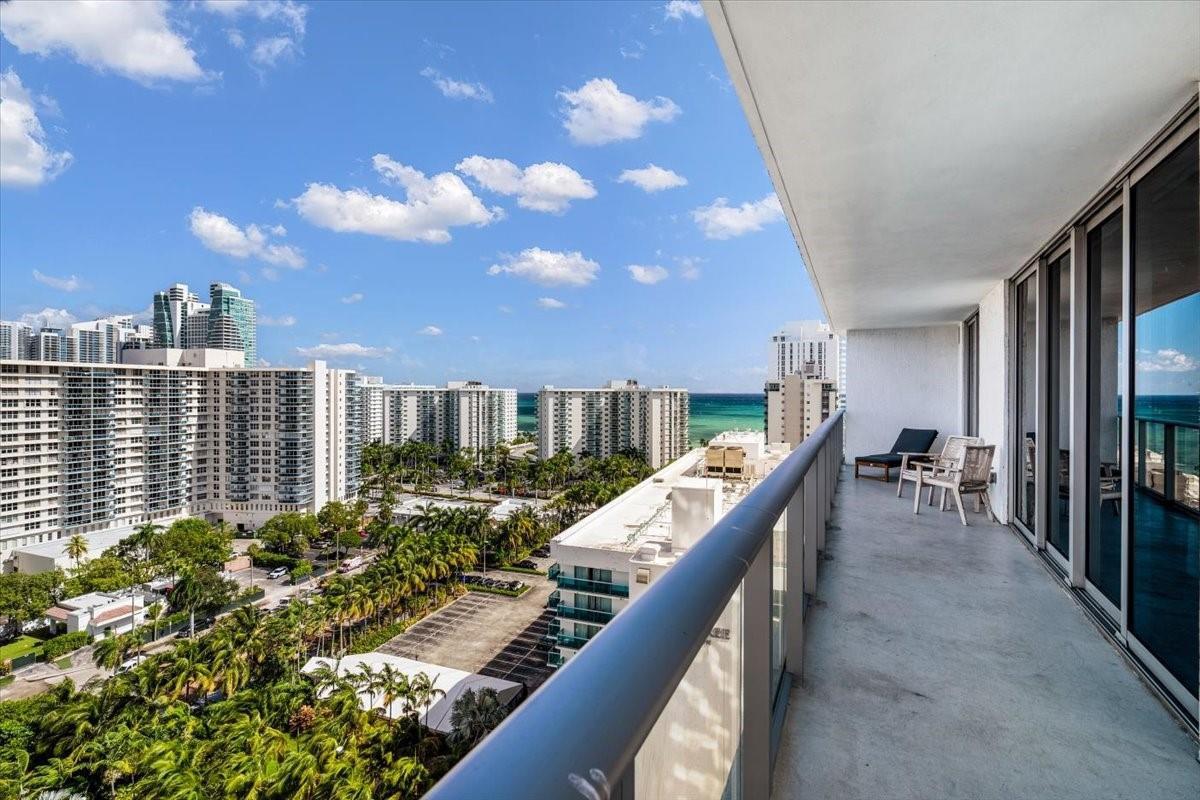 A high-rise balcony overlooks a coastal city with ocean views and lush green trees — 4010 S Ocean Drive # R1102, Hollywood FL 33019, HOLLYWOOD, FL