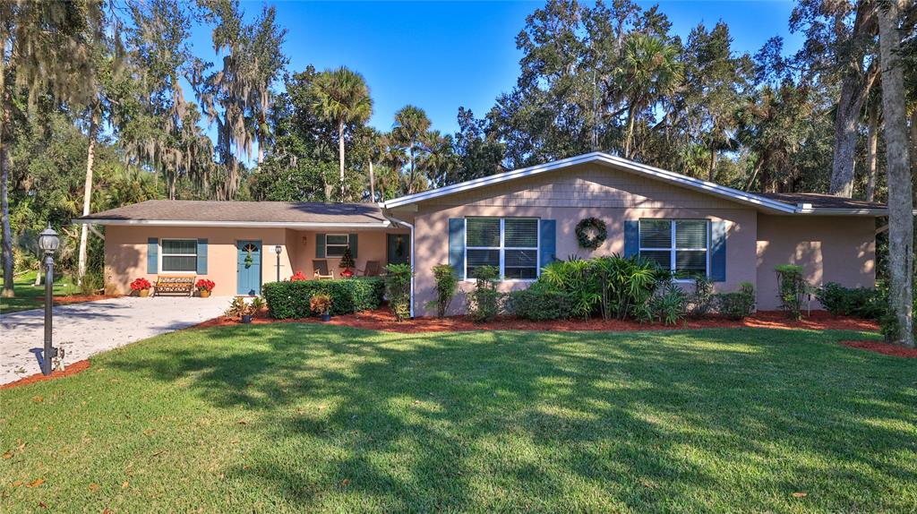 A single-story house with a tan exterior, blue shutters, and a large front lawn — 515 OLIVER DRIVE, NEW SMYRNA BEACH, FL