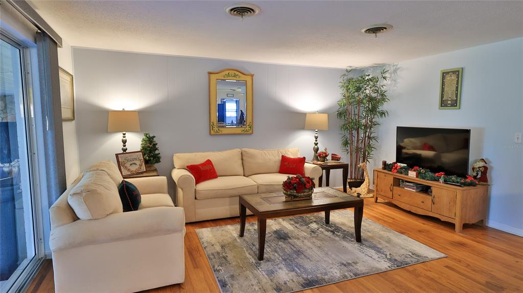 A living room features two beige sofas, a wooden coffee table, and a television console — 515 OLIVER DRIVE, NEW SMYRNA BEACH, FL