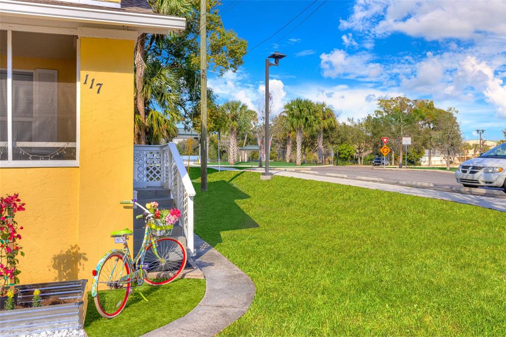 A yellow house exterior features a bicycle with a flower basket near the front steps — 117 E EUCLID AVENUE, DELAND, FL