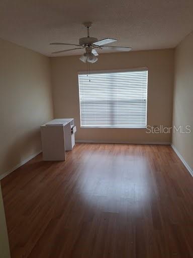 An empty room features wood-look flooring, a ceiling fan, and a white desk by a window — 2931 STILLWELL COURT, NEW PORT RICHEY, FL