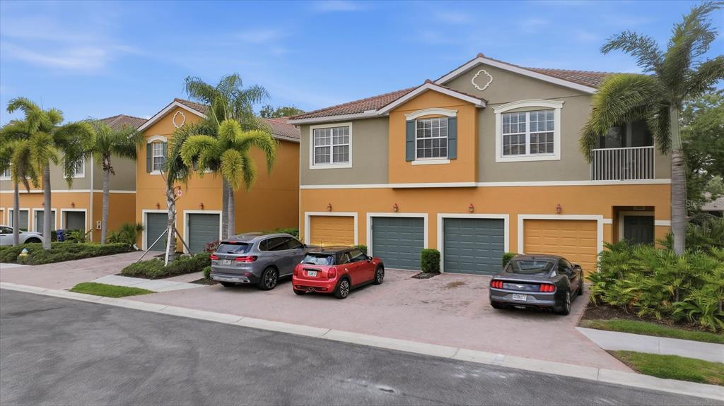 A row of two-story townhomes with attached garages and parked cars in the driveway — 7839 LIMESTONE LANE UNIT 12-204, SARASOTA, FL