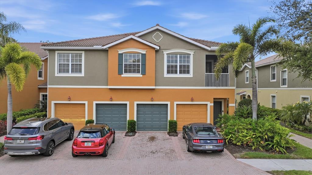 A two-story residential building with four garage doors and three parked cars in front — 7839 LIMESTONE LANE UNIT 12-204, SARASOTA, FL